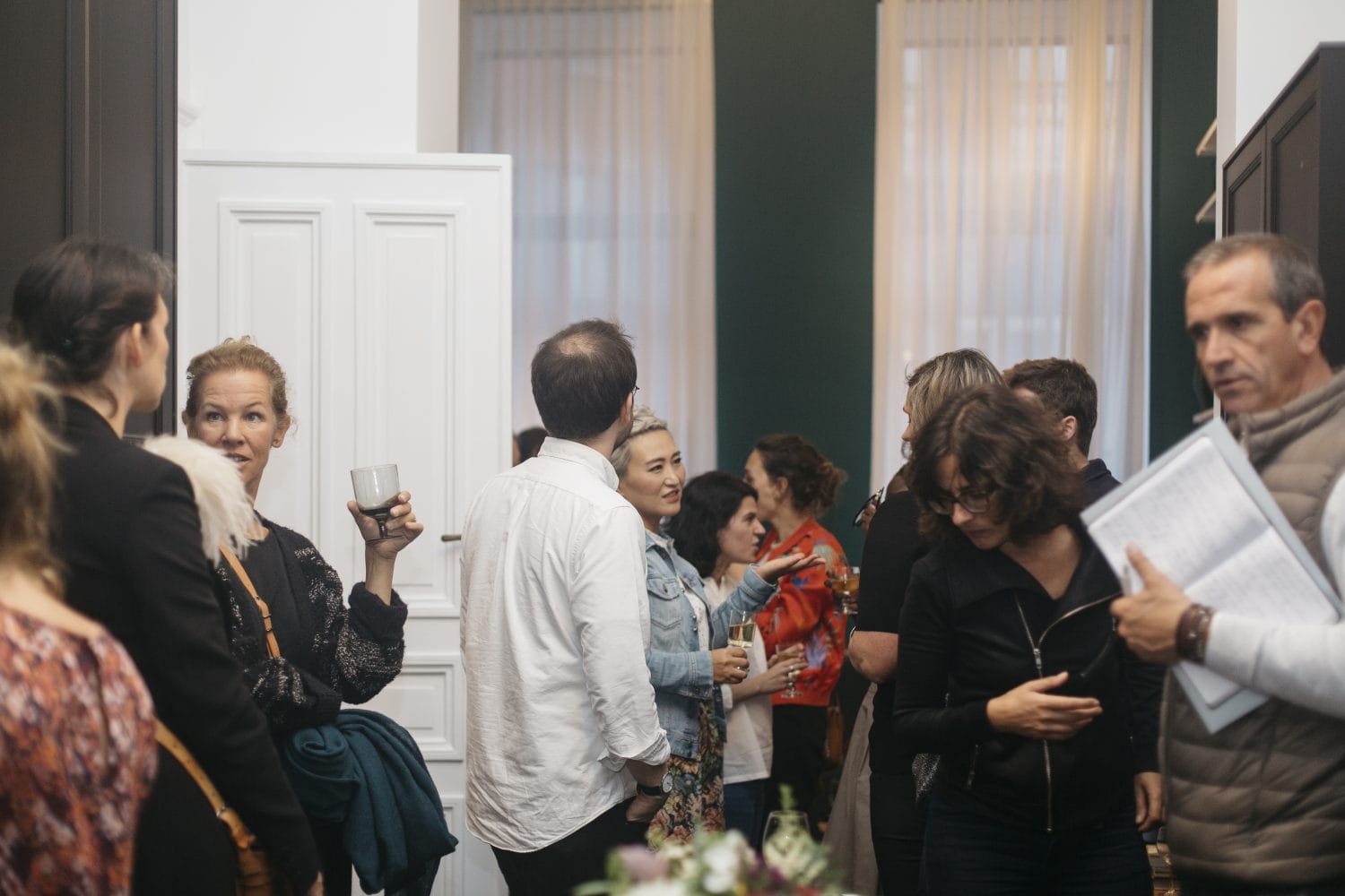 Young adults holding cocktails and enjoying conversation at Morton place coliving opening party 
