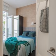 Chambre a couhcer avec lit recouvert d'un jet bleu ocean, meublée location Bruxelles