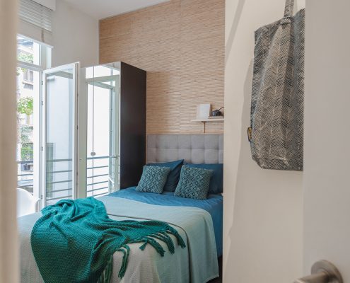 Chambre a couhcer avec lit recouvert d'un jet bleu ocean, meublée location Bruxelles