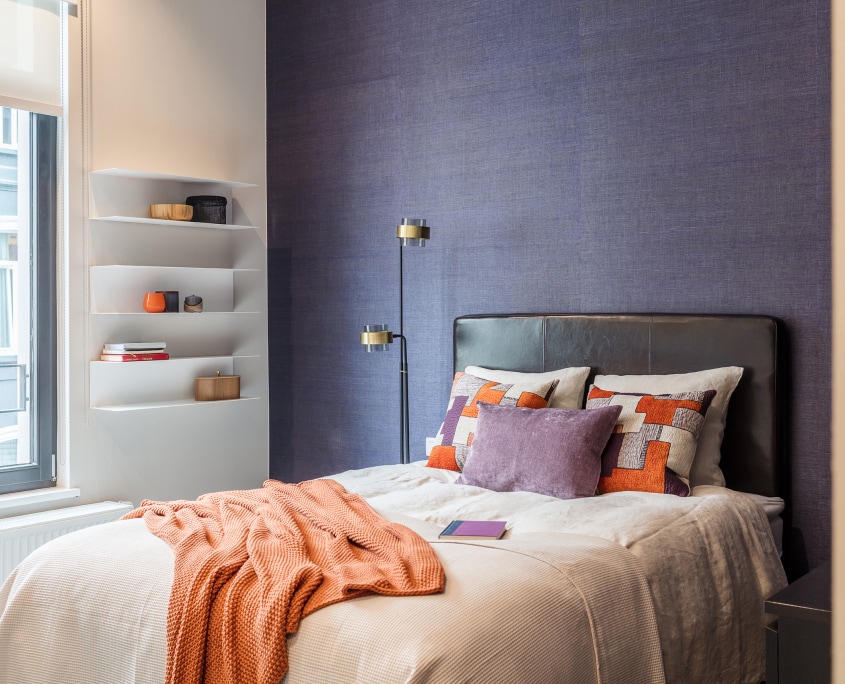 Bedroom with purple wallpaper and orange bedspread 